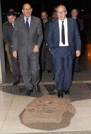 Hans Blix, U.N. chief inspector, right, and Mohammed Al-Baradei, head of the International Atomic Energy Agency, step on a mosaic of former U.S. President George Bush in the doorway of Ar-Rashid Hotel, Baghdad, November 2002.